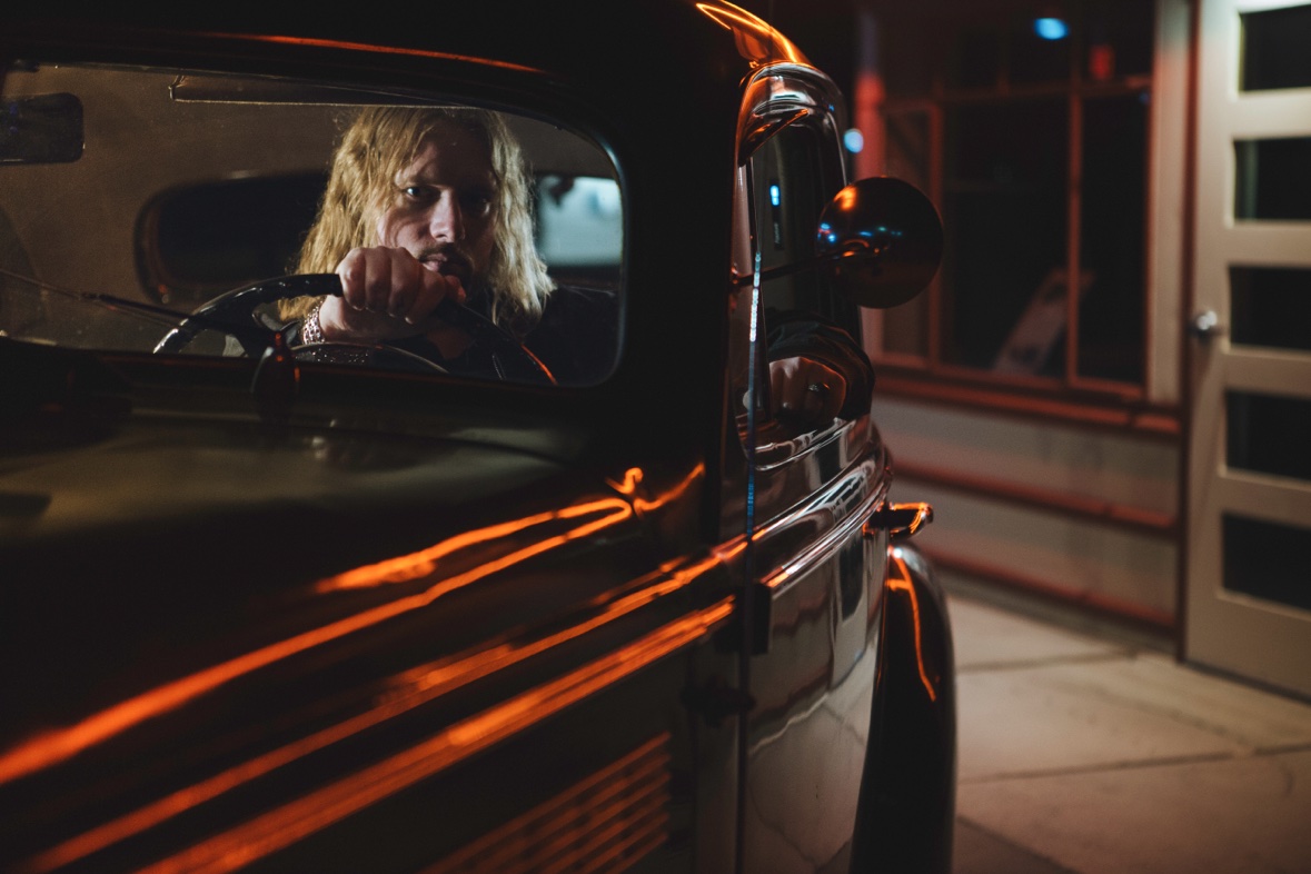 Micheal Sawyer behind the wheel of a vintage car at night